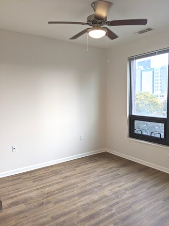 Apartment bedroom with ceiling fan, window, and hardwood floors_Beecher Terrace I, Louisville, KY